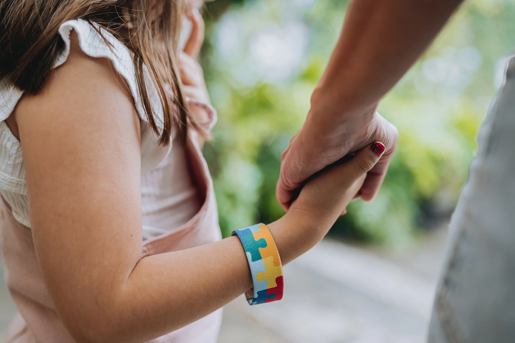 Close-up of an autistic child holds her mother's hand. Stock photo