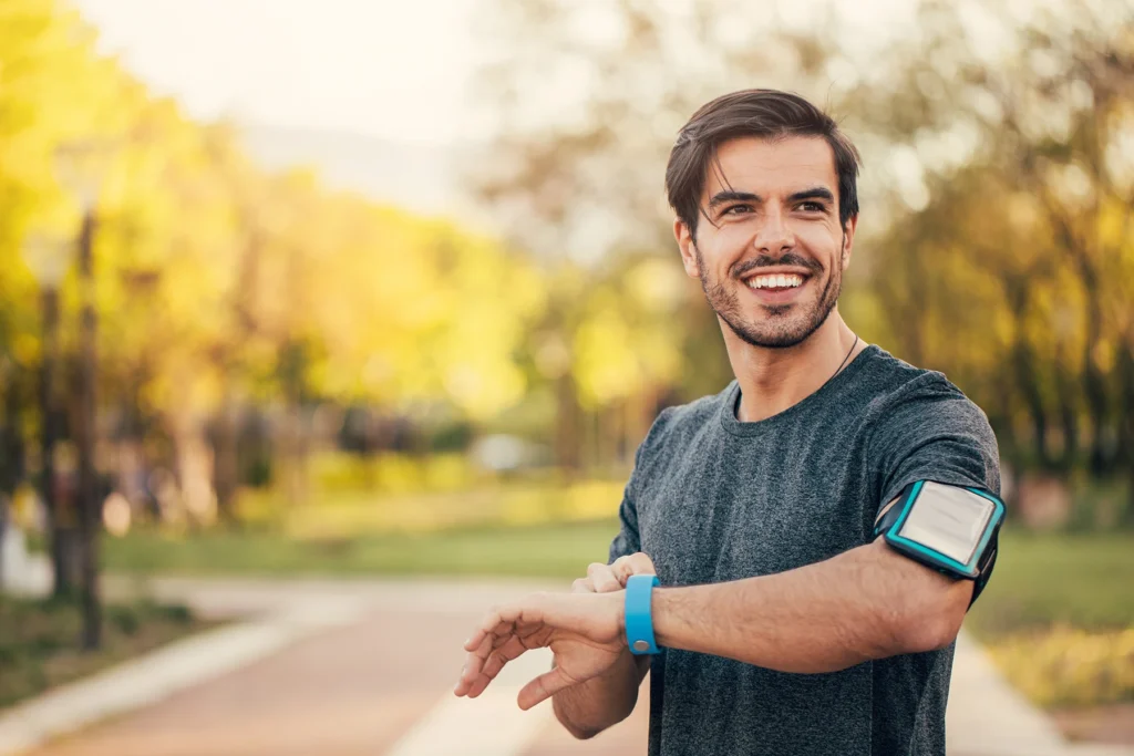 Smiling Hispanic man checks his heart rate on his watch.