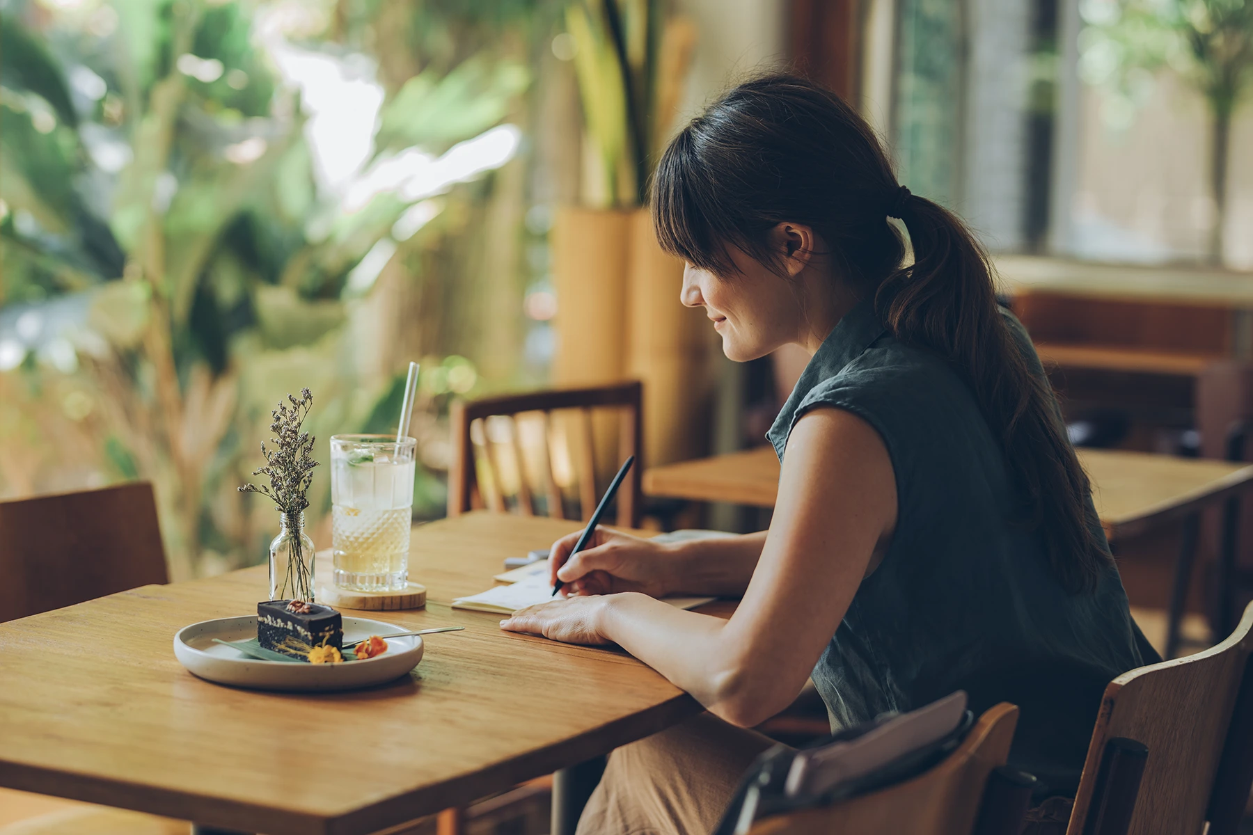 Young Woman Writing Notes in her Notebook while Sitting at a Cafe