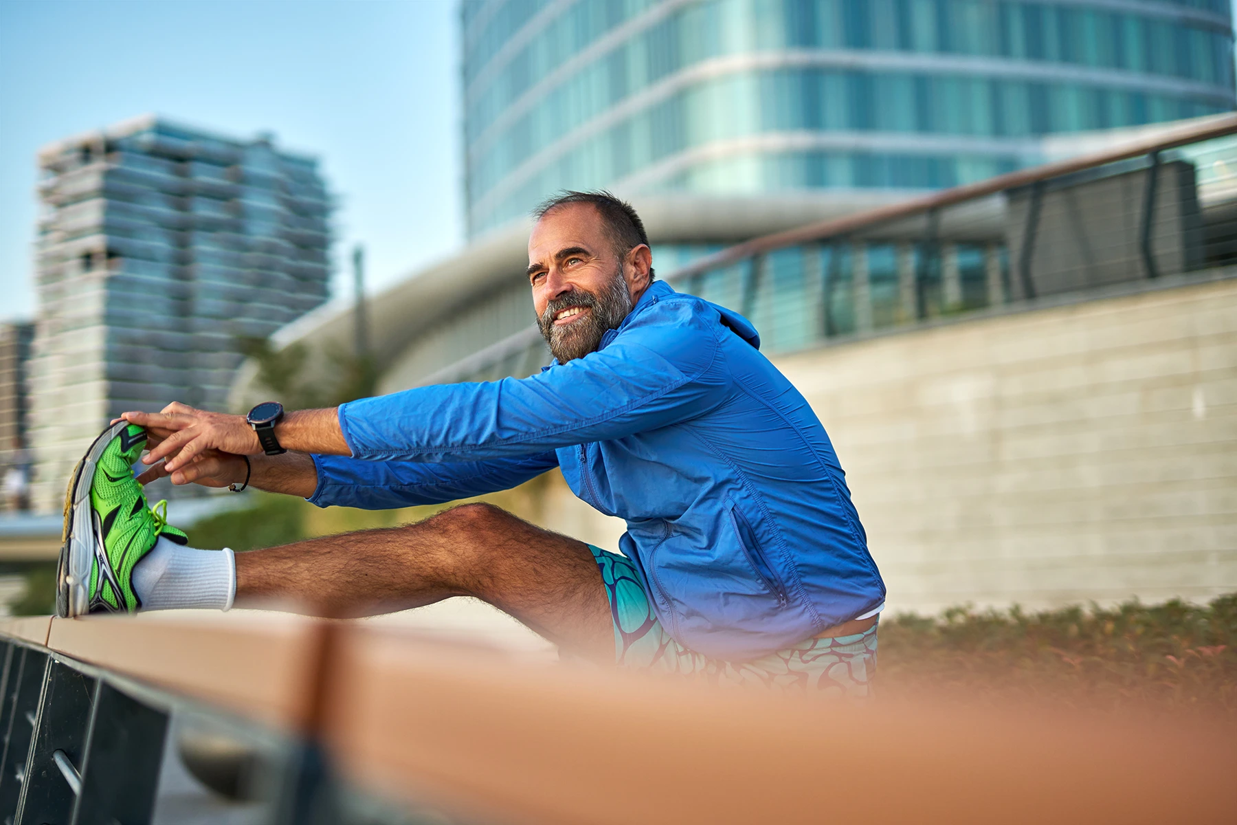 Mature adult man stretching leg during urban workout - stock photo