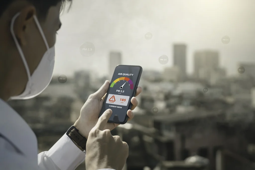 Physician in mask checking the air quality of city on his cell phone - stock photo.