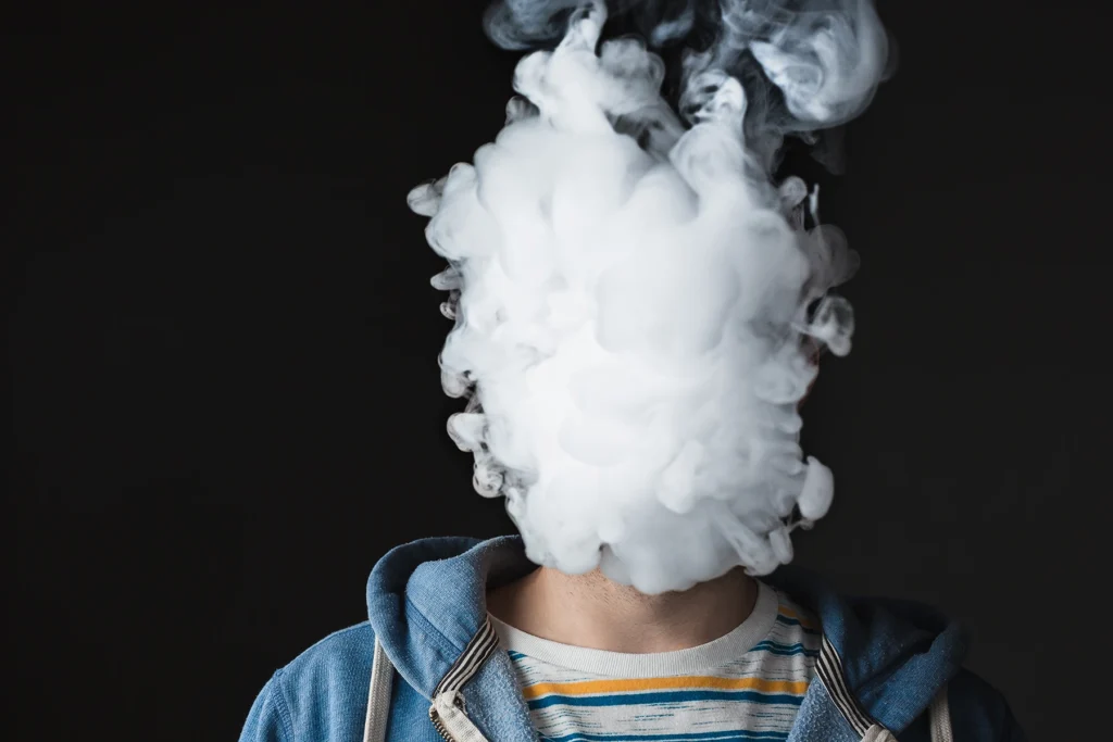 A cloud of vaping smoke covers a young boy's face. Stock image for health article.