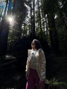 Woman in the woods looking toward the sun. Photo credit: Brittany Malo 