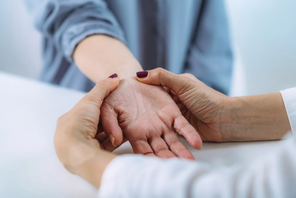 Doctor examining the hand of a senior patient with nerve pain