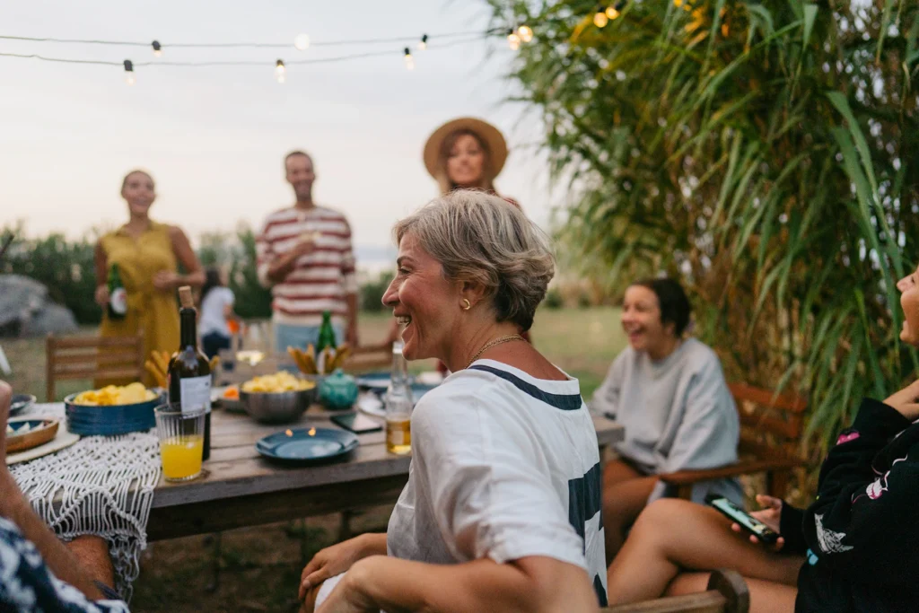 Photo of a woman enjoying the outdoor dinner party with her family and friends. - stock