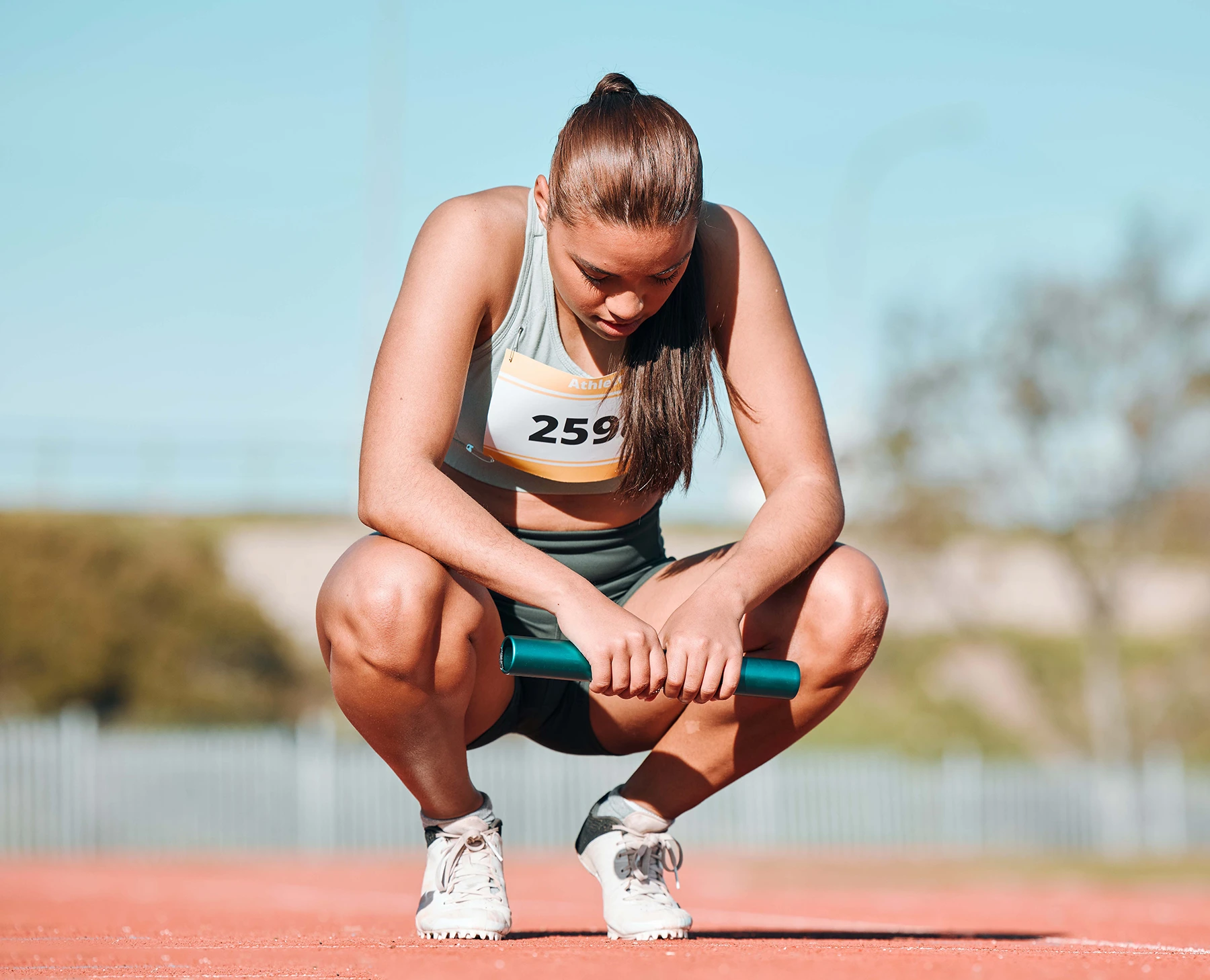 Woman athlete on track for a relay race, marathon or competition at a stadium. Sports, workout and young female runner resting with a baton for an outdoor cardio training exercise.