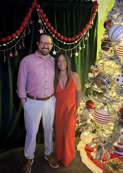 Efrain Hernández Pérez and spouse pose in front of the tree during the holidays.