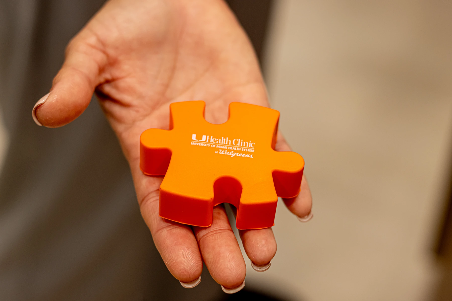 Hand holding orange squeeze toy, highlighting UHealth Clinic at Walgreens autism-friendly clinic designation.