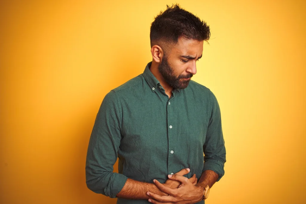 Man wearing elegant shirt standing over isolated white background with hand on stomach because nausea, painful disease feeling unwell. Ache concept. - stock photo