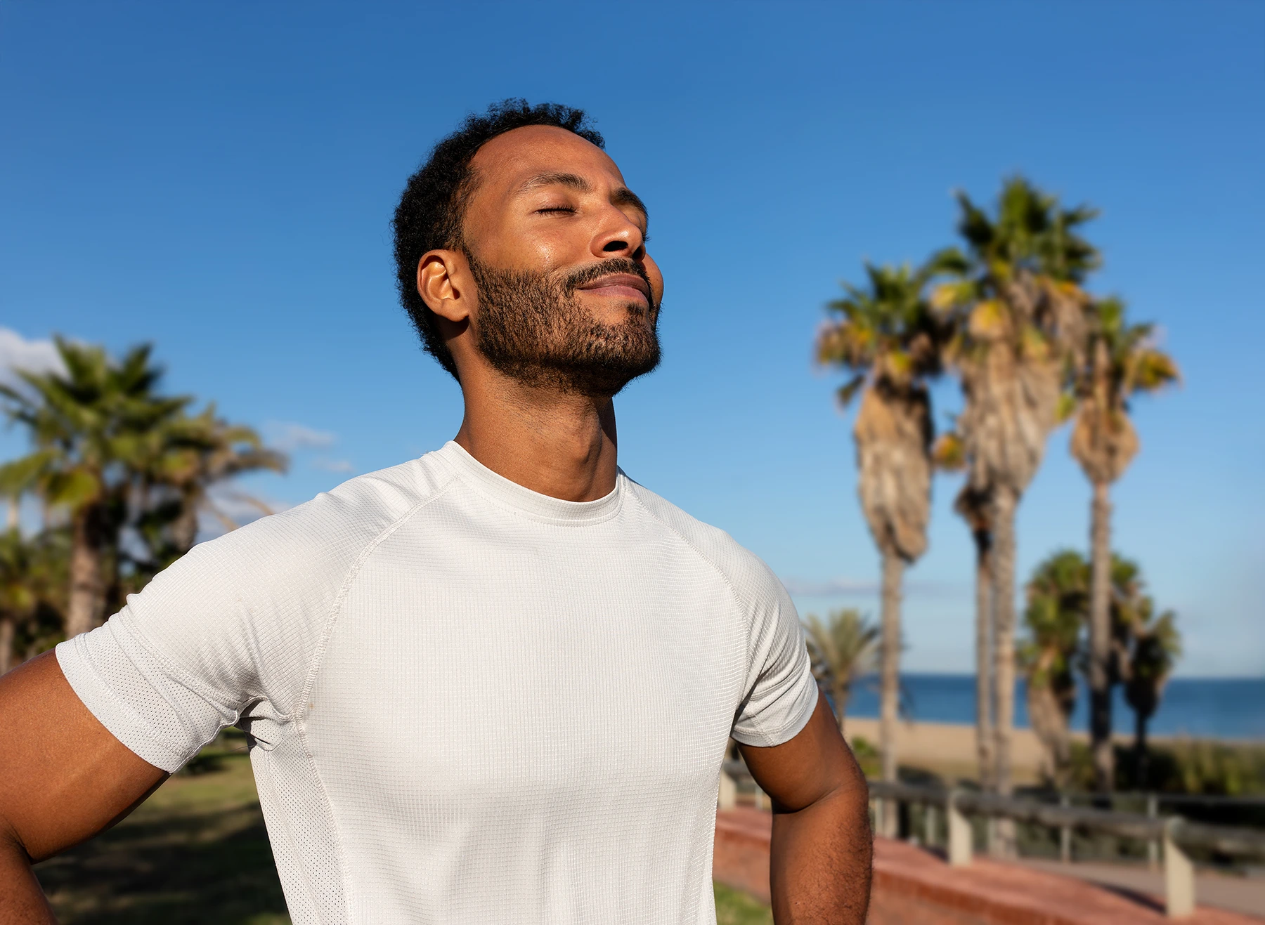 African American man breathing deeply in nature. Black man in sports clothing feeling good after exercising. - stock photo