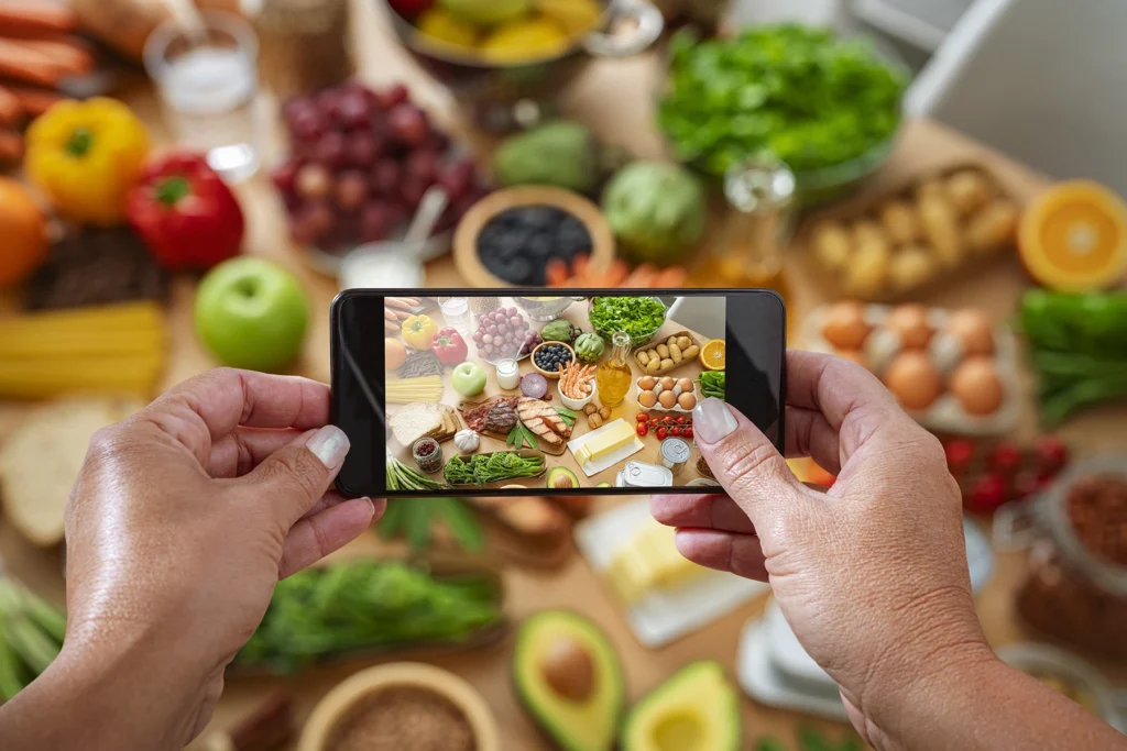 Woman photographing a table filled with large variety of food including options for fiber- stock photo