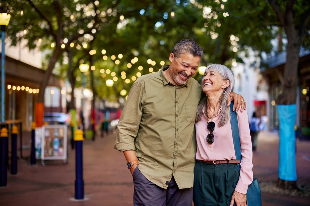 Smiling older couple enjoys retirement and walks together on a city street. - Stock photo