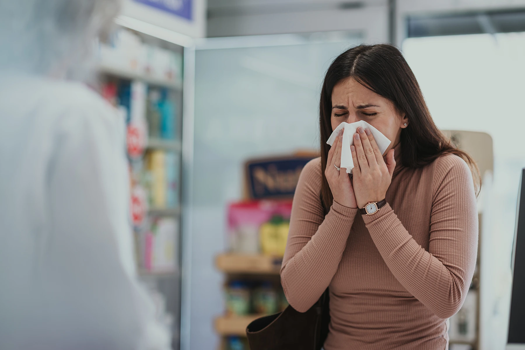 Woman sneezing in pharmacy seeking allergy relief - stock photo