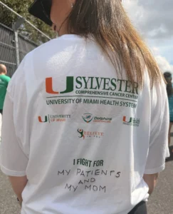 Dr. Perez, breast cancer doctor, shows the back of her race day shirt where it says "I fight for my patients and my mom."