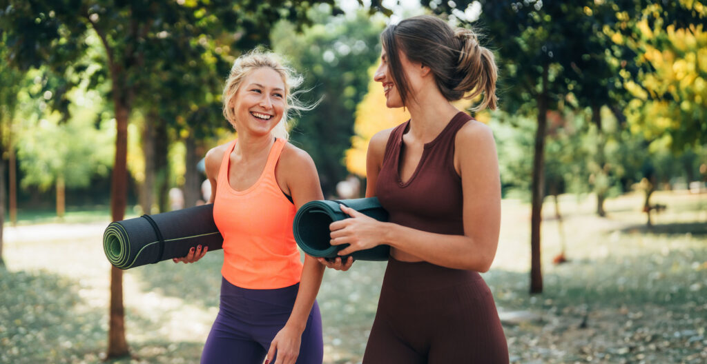 Young sporty women holding yoga mats and having fun while preparing for exercise