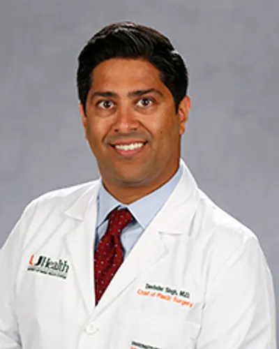 Dr. Devinder Singh, in white medical coat and red tie, posing for portrait