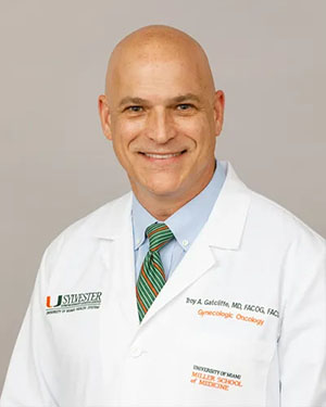 Dr. Troy Gatliffe, smiling and wearing a white medical coat with a green tie