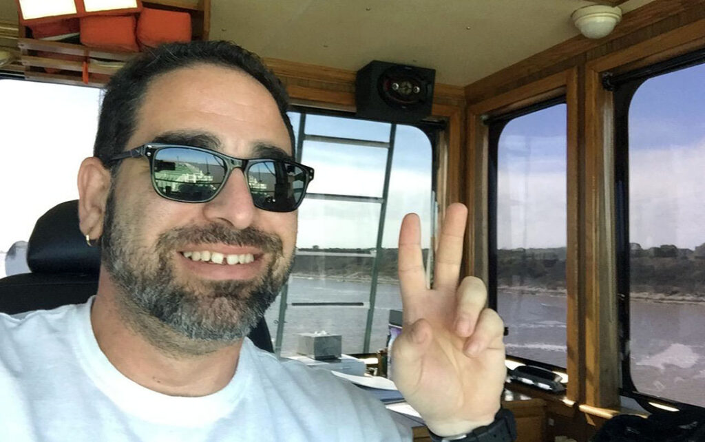Red Gonzalez inside a truck cabin in a personal photograph. He is smiling and giving a peace sign.