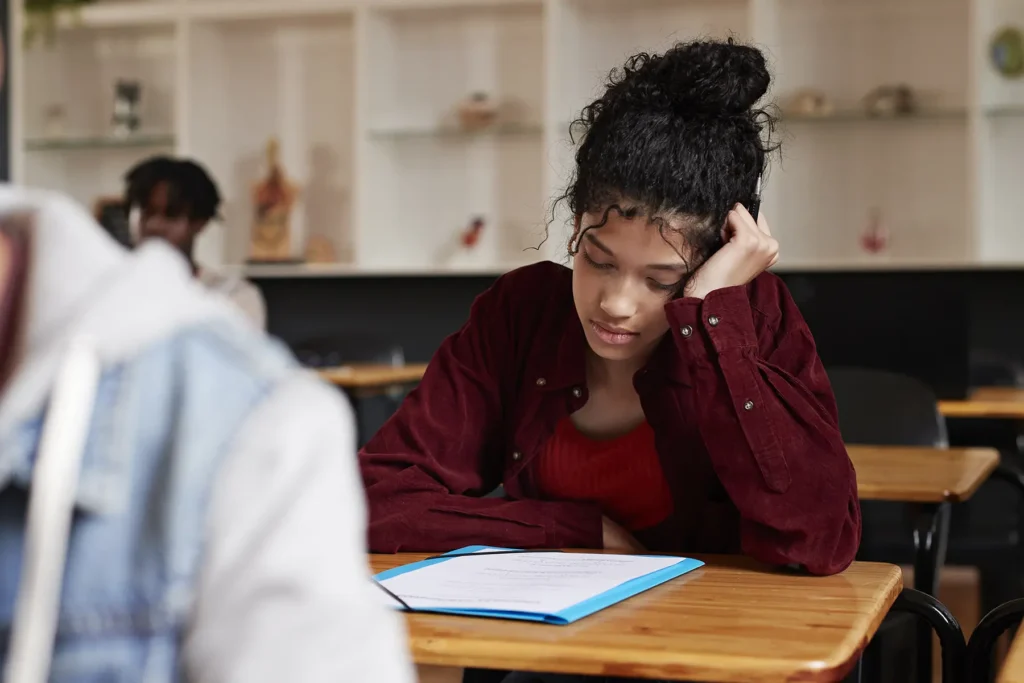 Tensed teenage girl staring at paper during exam - stock photo