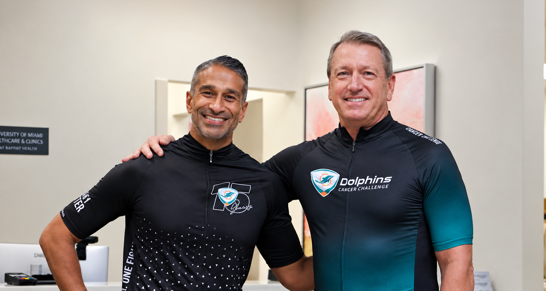 Dr. Sanoj Punnen and Chris O'Shea, smiling and standing side by side while wearing Dolphins Cancer Challenge biking gear