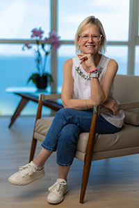 Jennifer Buttrick sits comfortably in her home, photographed in a bright indoor setting with natural light.